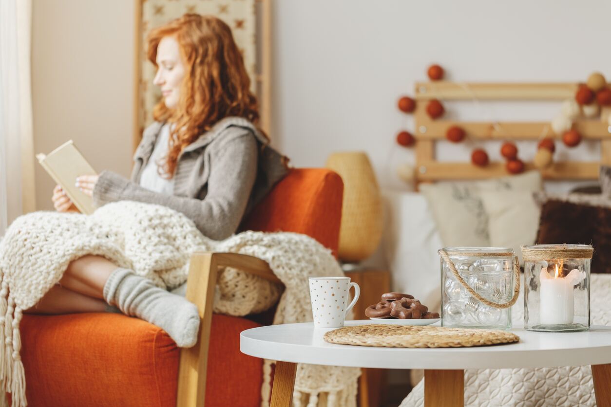 Woman reads book in autumnal bedroom 