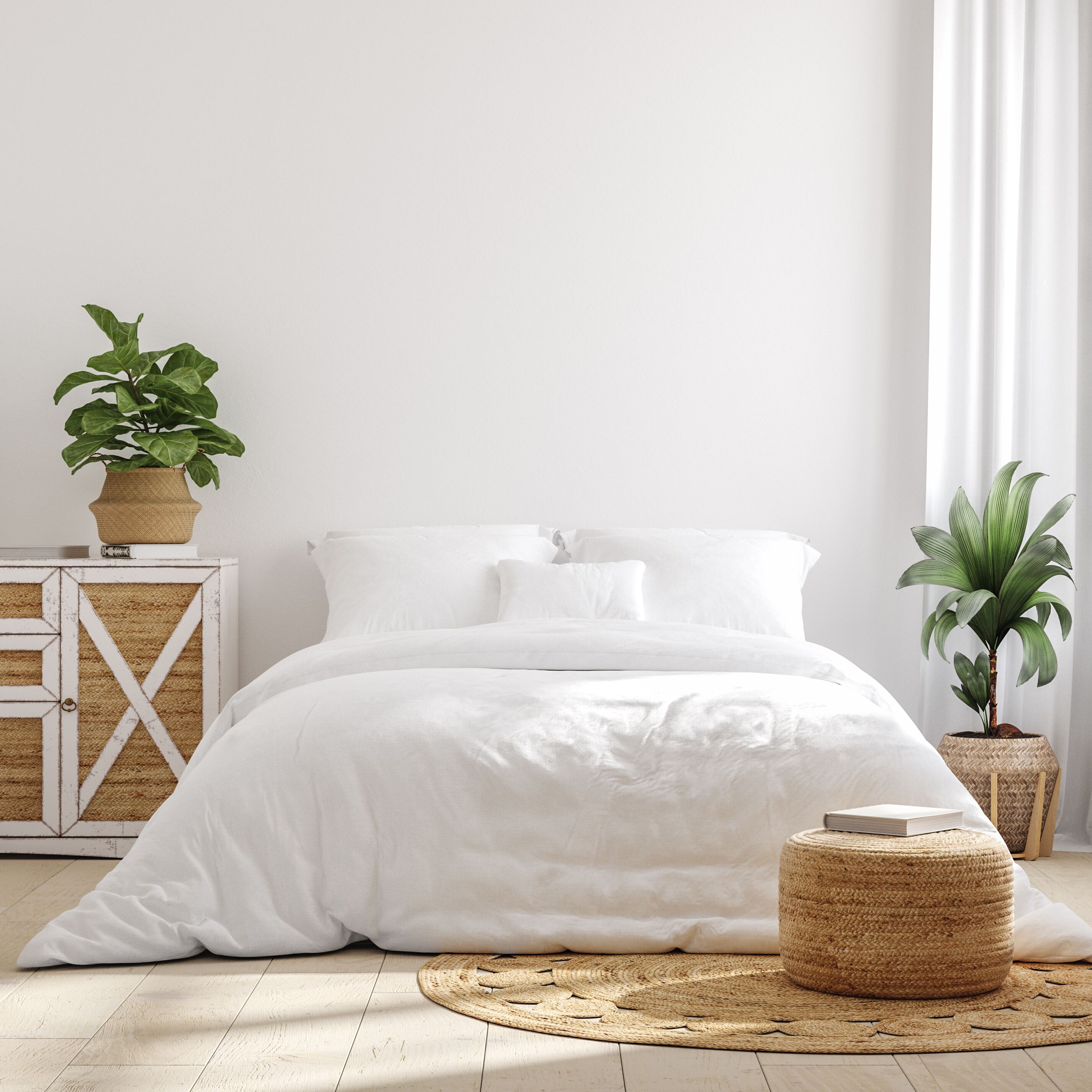 Comfortable white bedding on a bed surrounded by rattan furniture and plants