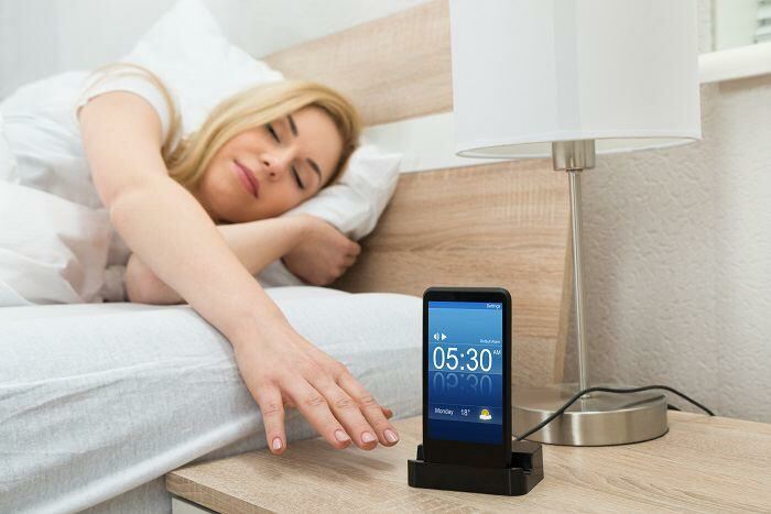 Woman reaching out to bedside alarm clock
