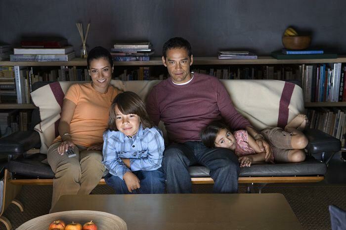 Family relaxing on couch watching TV