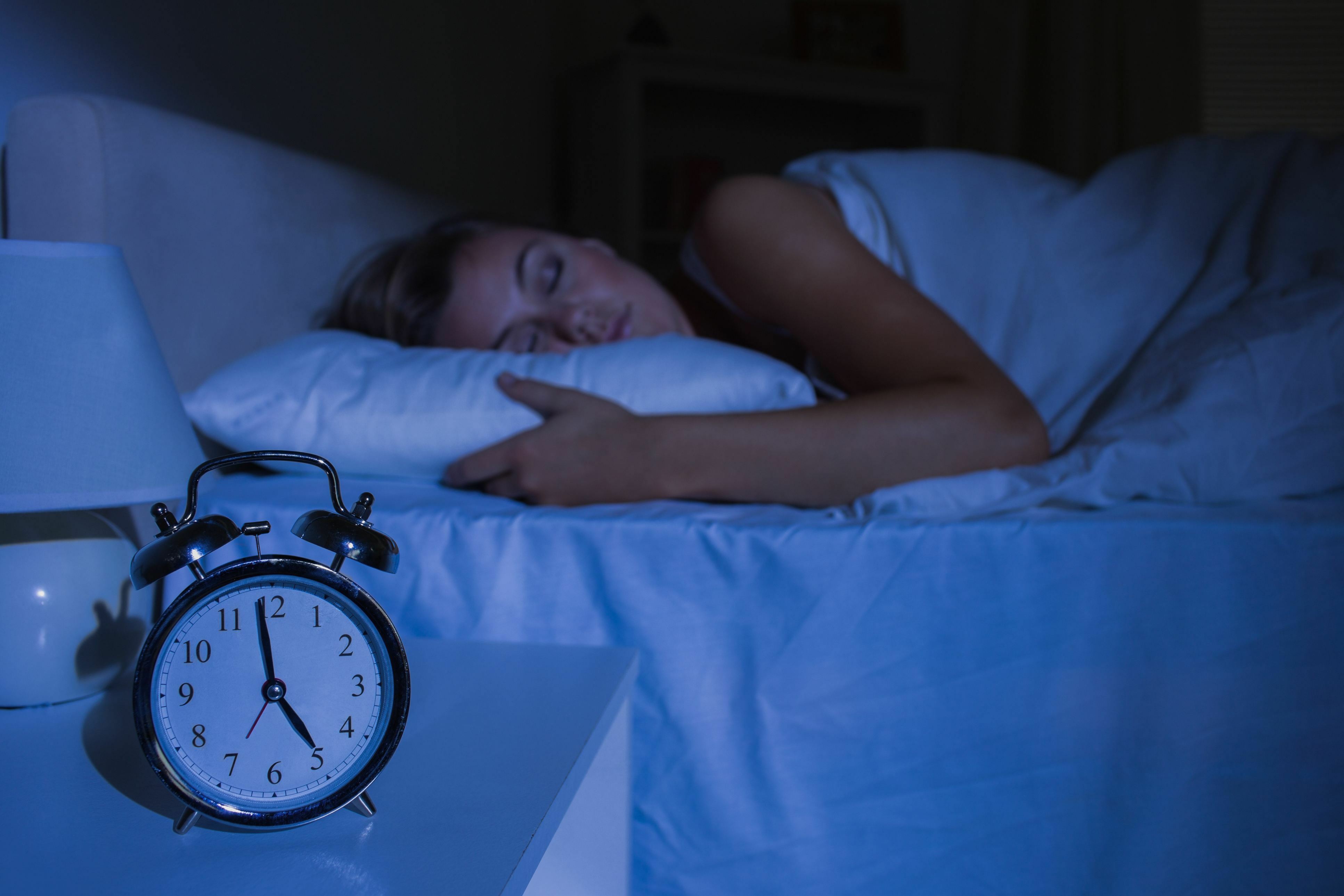 Woman sleep next to an alarm clock