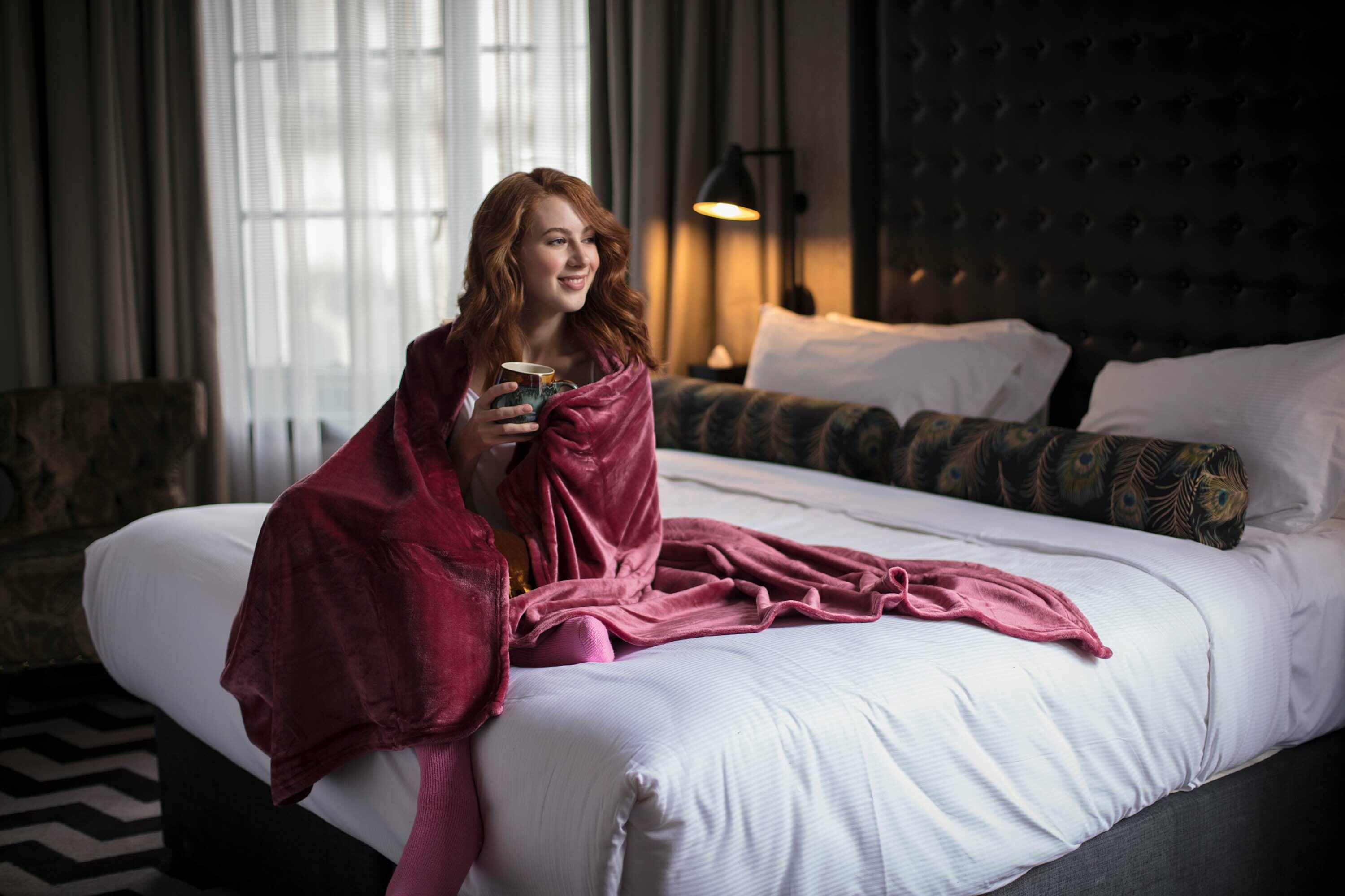 Woman sitting on bed covered with a warm blanket