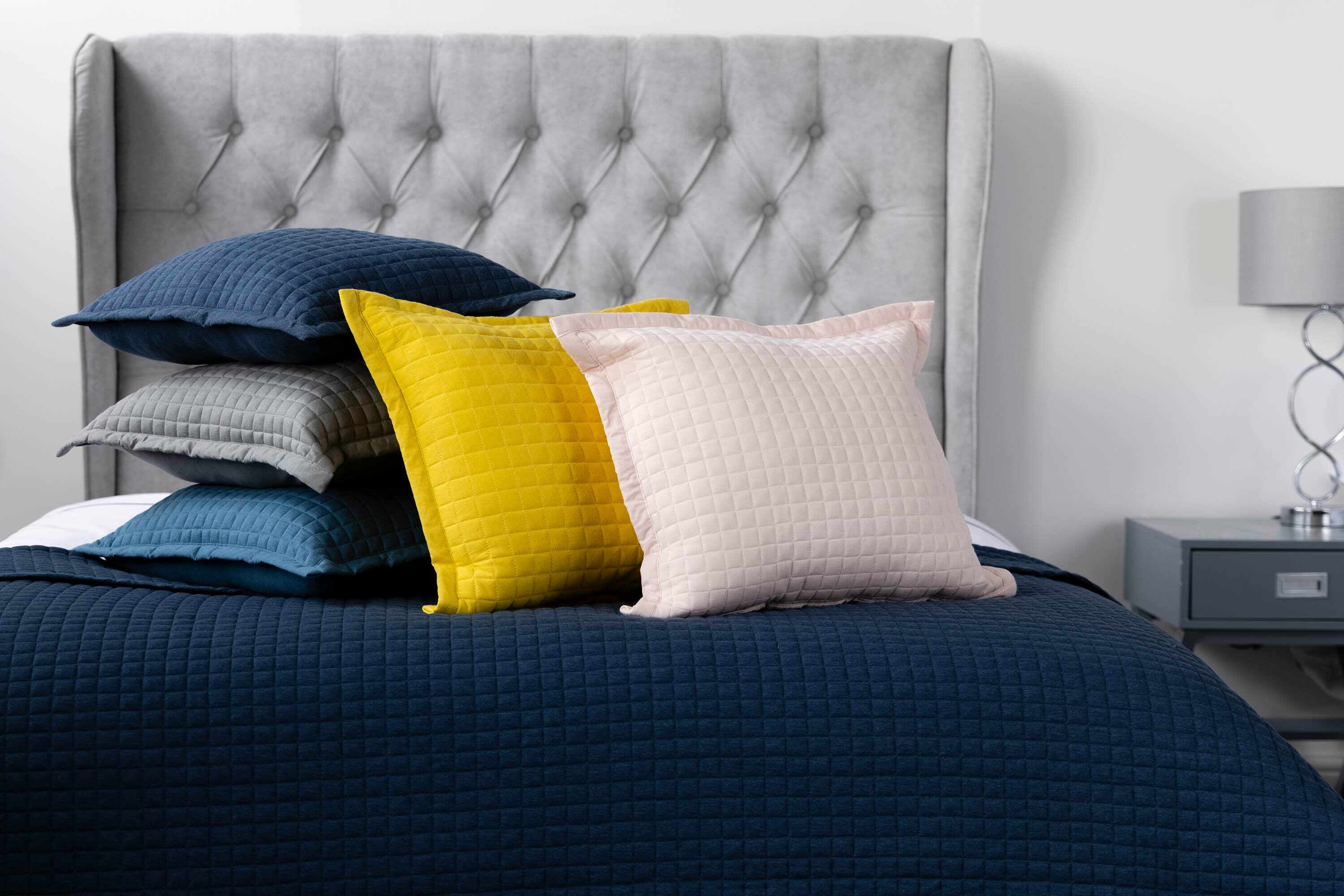 Colourful cushions stacked on bed