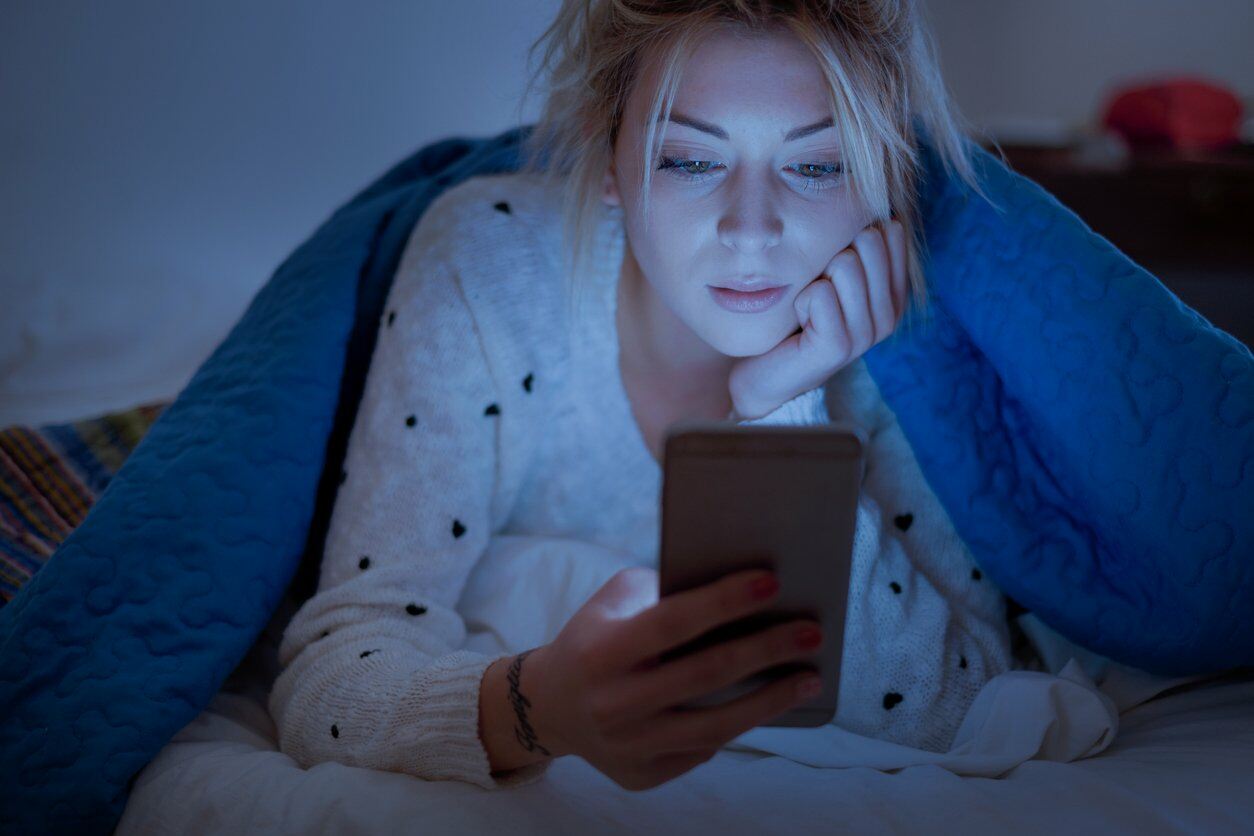 Woman using Mobile Phone in bed
